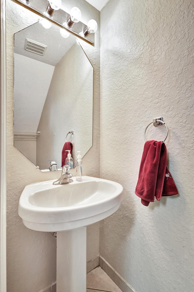 bathroom featuring tile patterned flooring, sink, and vaulted ceiling