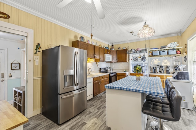 kitchen featuring white appliances, crown molding, a center island, light wood-style floors, and brown cabinets
