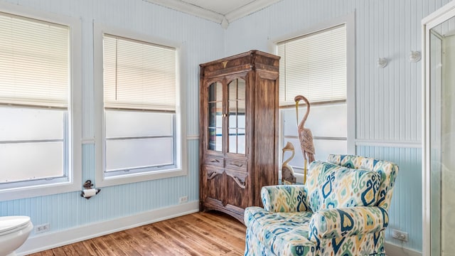 living area featuring crown molding, baseboards, and wood finished floors