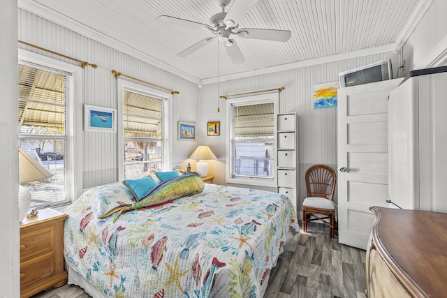 bedroom with crown molding, dark wood-style floors, and a ceiling fan