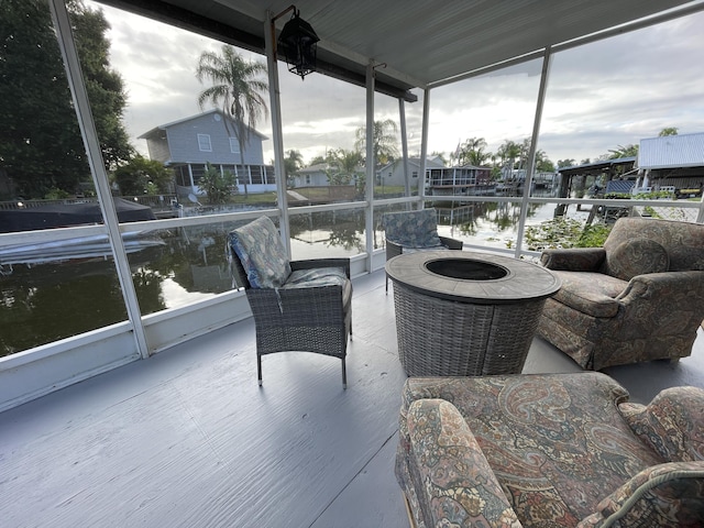 sunroom / solarium featuring a fire pit, plenty of natural light, and a water view