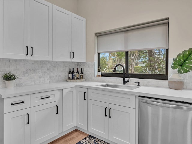 kitchen featuring tasteful backsplash, white cabinetry, sink, and stainless steel dishwasher