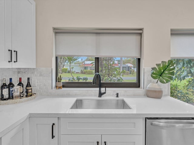 kitchen with white cabinetry, sink, decorative backsplash, and dishwasher