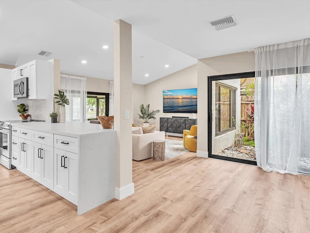 kitchen featuring white cabinetry, decorative backsplash, appliances with stainless steel finishes, and light hardwood / wood-style flooring