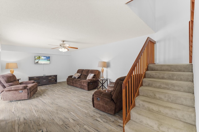 living area featuring stairs, ceiling fan, and wood finished floors