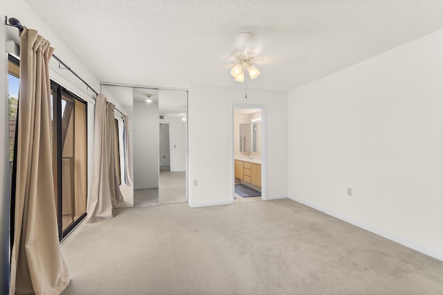 unfurnished bedroom with baseboards, light carpet, ensuite bathroom, a textured ceiling, and access to outside