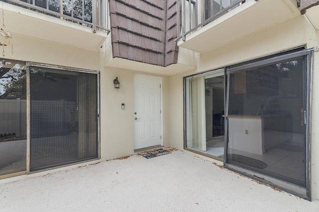 property entrance featuring a patio, a balcony, and stucco siding