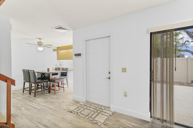 entryway with visible vents, a textured ceiling, light wood-type flooring, and ceiling fan