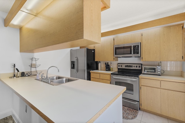 kitchen featuring a peninsula, light brown cabinets, appliances with stainless steel finishes, and a sink