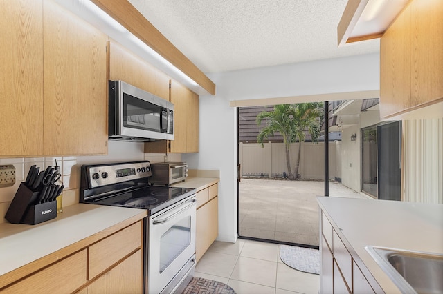 kitchen with a textured ceiling, stainless steel appliances, light tile patterned flooring, a toaster, and light countertops