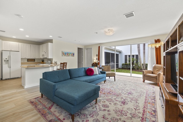 living area featuring light wood finished floors, visible vents, and recessed lighting