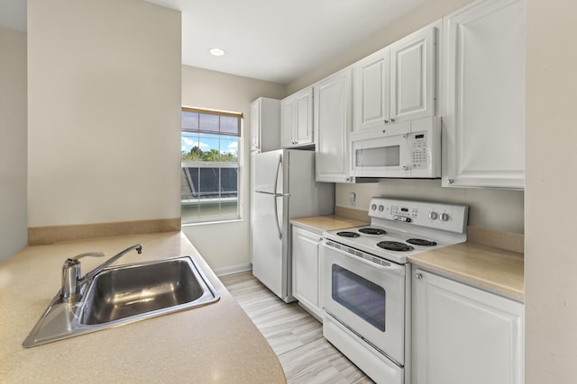 kitchen with white appliances, white cabinets, and a sink