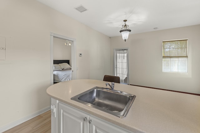 kitchen with light wood-type flooring, visible vents, light countertops, and a sink