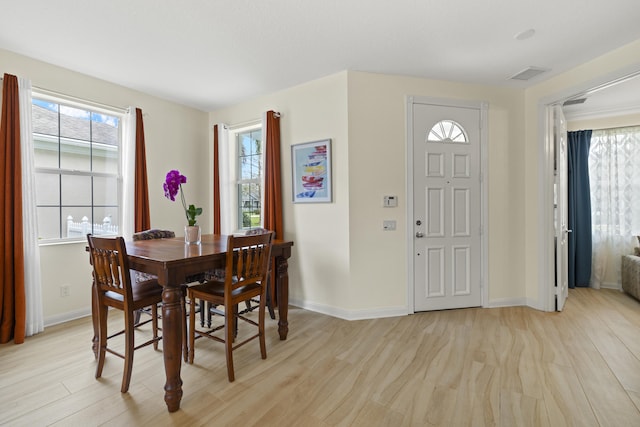 dining space with light wood-type flooring, visible vents, and baseboards