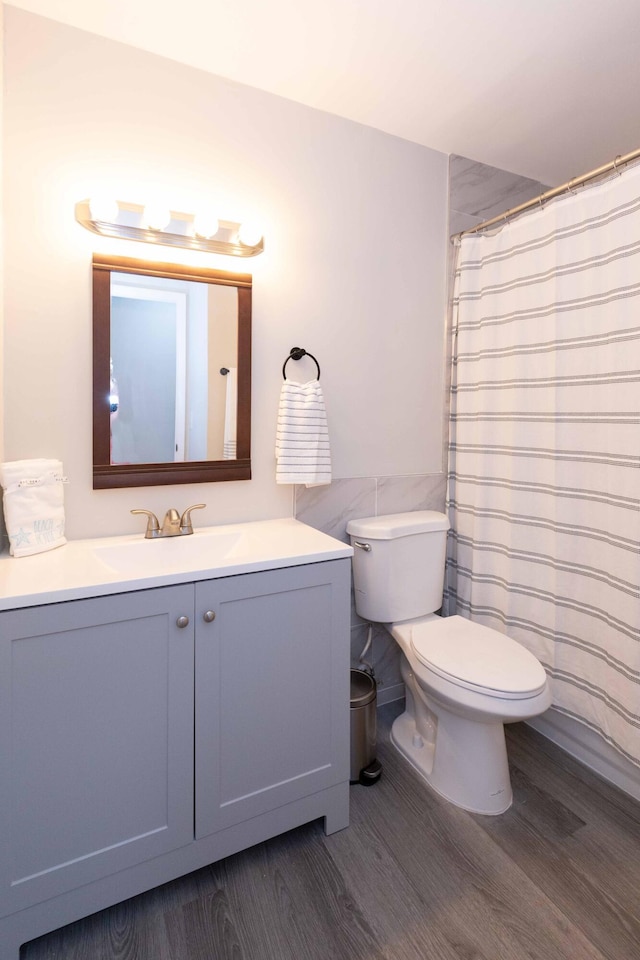 bathroom with toilet, a shower with curtain, wood finished floors, and vanity