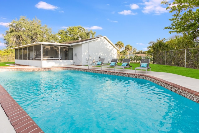 view of swimming pool with a patio, fence, a sunroom, a lawn, and a fenced in pool