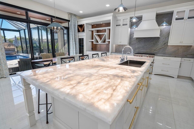 kitchen featuring an island with sink, a breakfast bar, and premium range hood