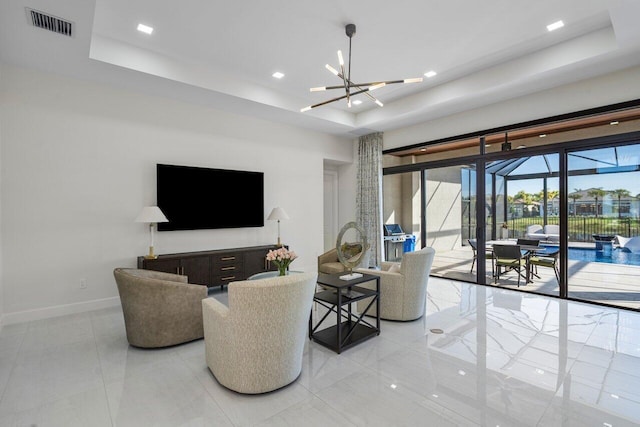 living room with an inviting chandelier and a tray ceiling