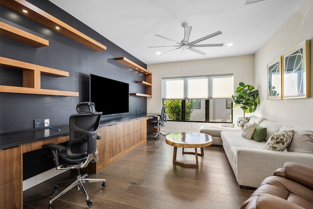 living room featuring ceiling fan, dark hardwood / wood-style floors, and built in desk