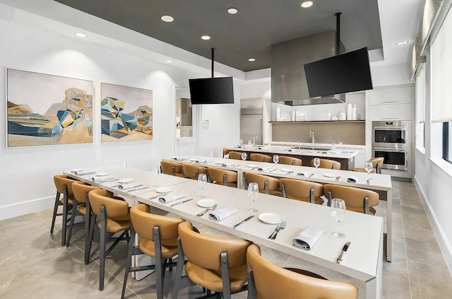 kitchen with a breakfast bar, a center island, double oven, decorative backsplash, and white cabinets