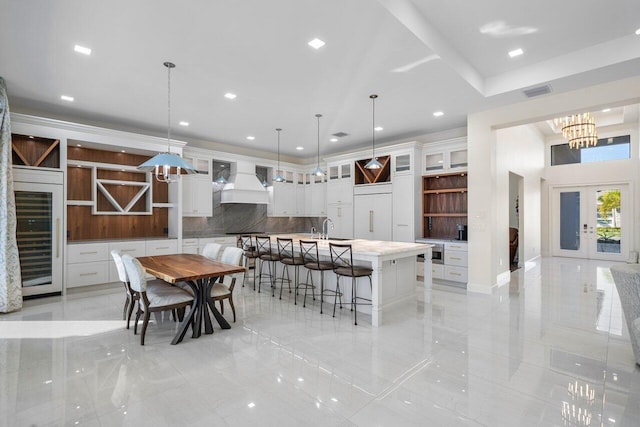 dining room with sink, a notable chandelier, beverage cooler, and french doors