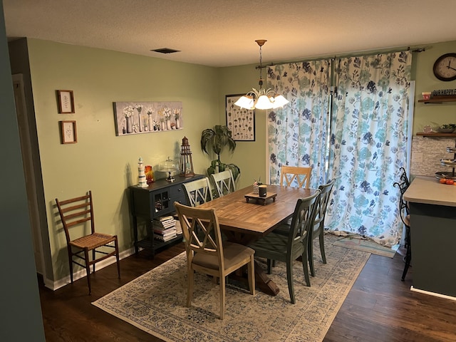 dining room featuring dark wood-type flooring, a textured ceiling, and a chandelier