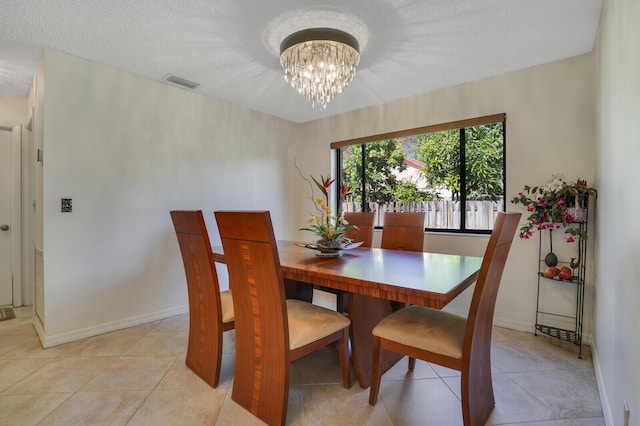 tiled dining area with a textured ceiling and a chandelier