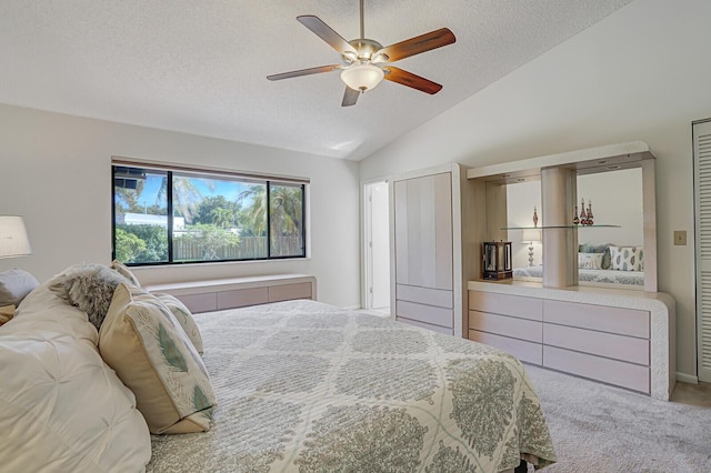 bedroom featuring light carpet, ceiling fan, vaulted ceiling, and a textured ceiling