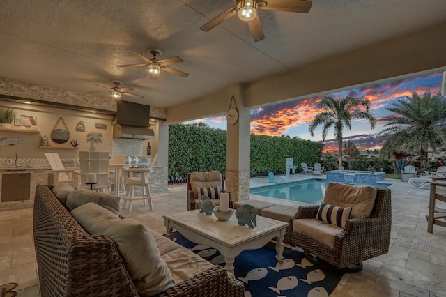 patio terrace at dusk featuring a fenced backyard, a sink, an outdoor living space, and area for grilling