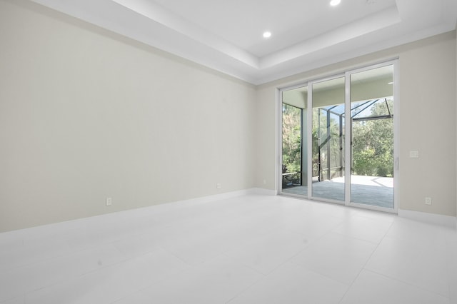 spare room with recessed lighting, a raised ceiling, and baseboards