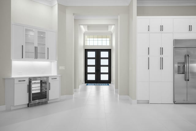 foyer with light tile patterned floors, beverage cooler, baseboards, french doors, and ornamental molding