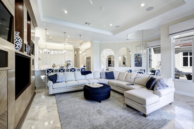 living room with crown molding, a notable chandelier, and a tray ceiling