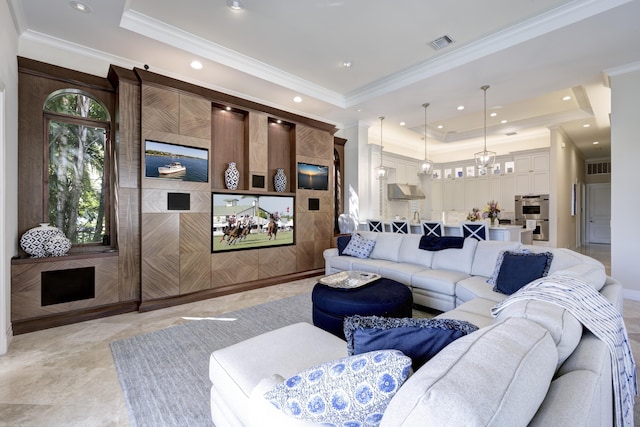 living room featuring a raised ceiling, ornamental molding, and a notable chandelier