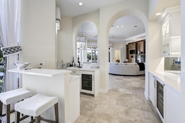 kitchen featuring wine cooler, decorative light fixtures, a kitchen breakfast bar, and white cabinets