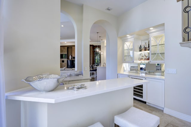 bar featuring white cabinetry, beverage cooler, and crown molding