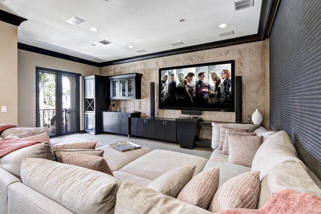 carpeted cinema room with crown molding, indoor bar, and french doors