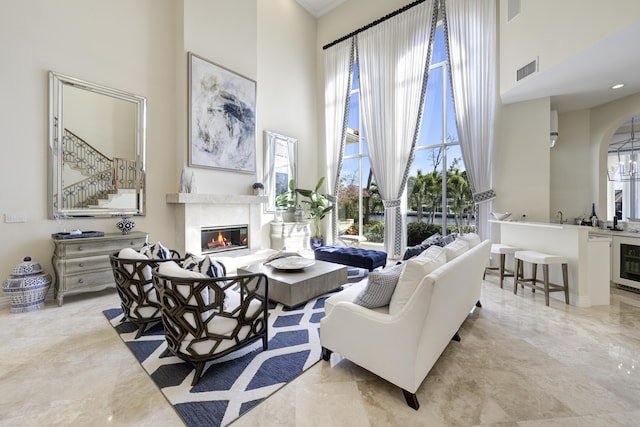 sitting room featuring a towering ceiling, a wealth of natural light, and beverage cooler