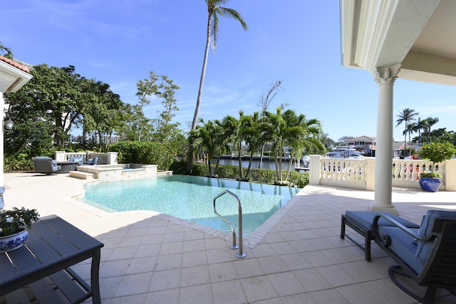 view of swimming pool featuring an in ground hot tub, a water view, and a patio area