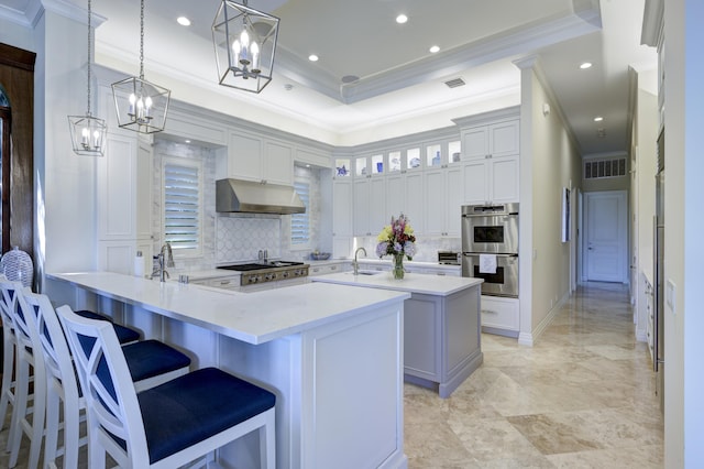 kitchen featuring decorative light fixtures, sink, a kitchen breakfast bar, ornamental molding, and kitchen peninsula