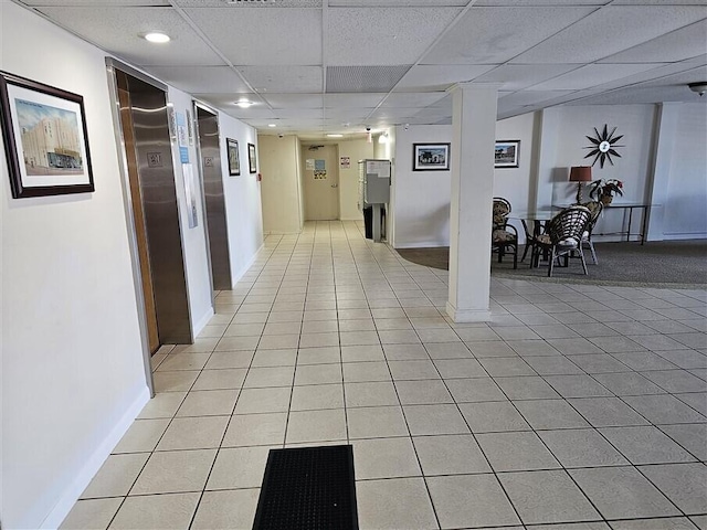 corridor featuring light tile patterned floors and a drop ceiling