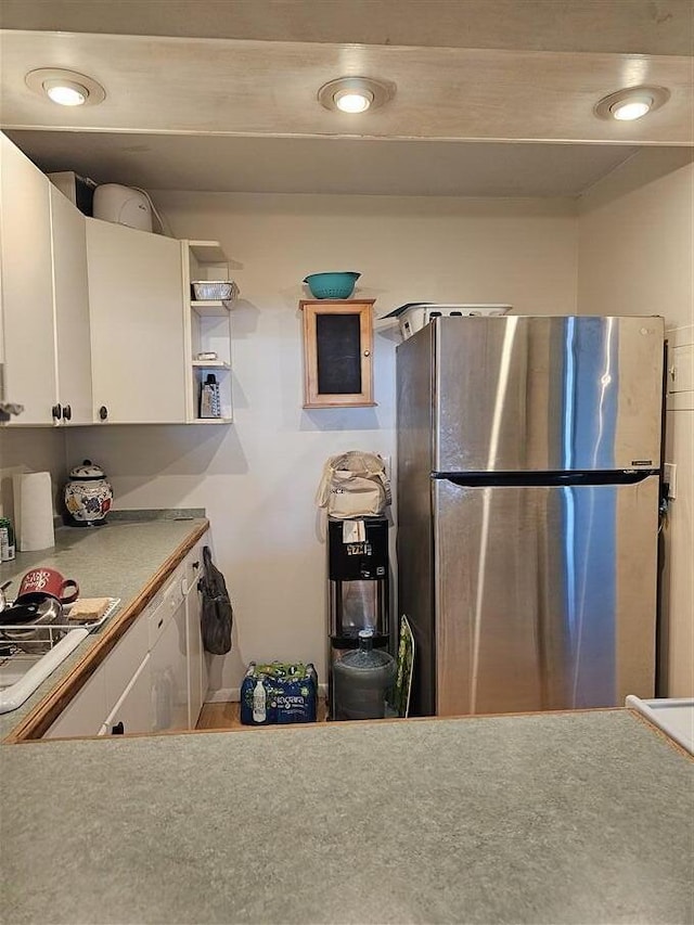 kitchen with stainless steel refrigerator and white cabinetry