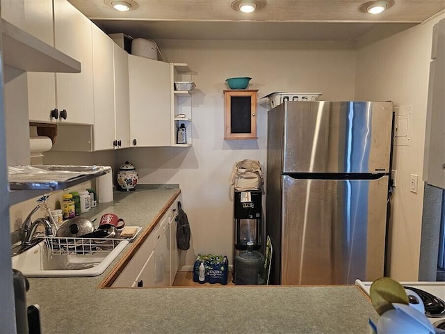 kitchen featuring white cabinetry, sink, and stainless steel refrigerator