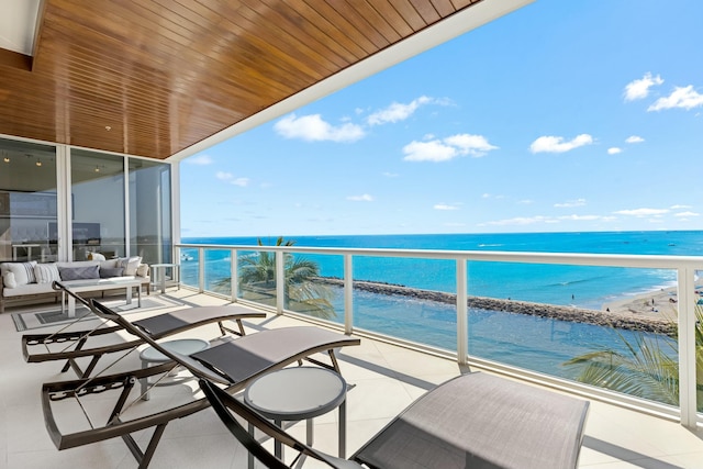 balcony with a water view, a beach view, and an outdoor living space