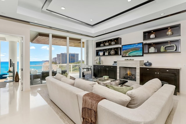 living area with recessed lighting, a raised ceiling, and a high end fireplace