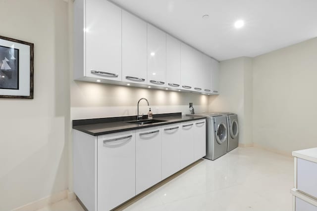 laundry room with light tile patterned floors, a sink, baseboards, cabinet space, and washer and clothes dryer