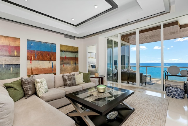 living room featuring a tray ceiling, floor to ceiling windows, recessed lighting, a water view, and visible vents