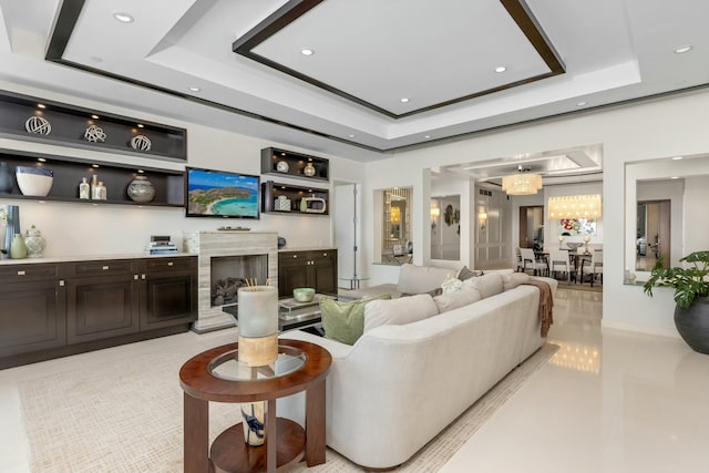 living room featuring an inviting chandelier, a fireplace, a raised ceiling, and recessed lighting