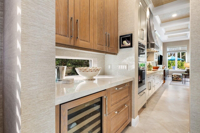 kitchen featuring light stone counters, stainless steel oven, refrigerator, beamed ceiling, and beverage cooler