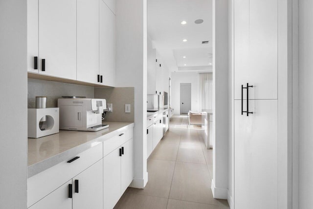 interior space with light tile patterned floors, white cabinets, and backsplash