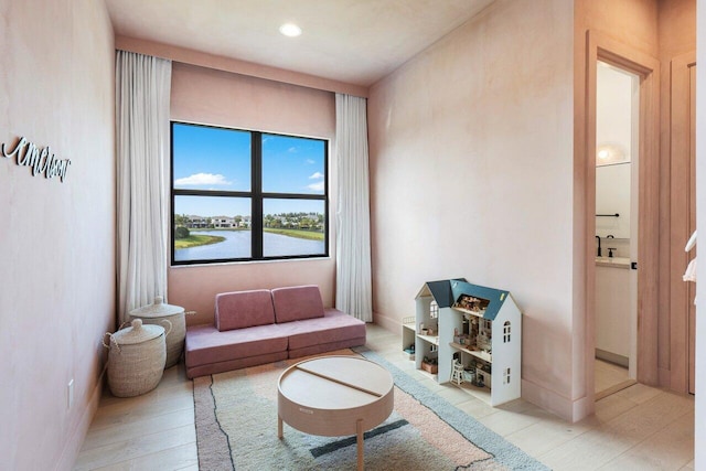 living area with light wood-type flooring and a water view